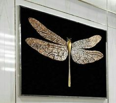 a black and gold dragonfly painting hanging on a wall