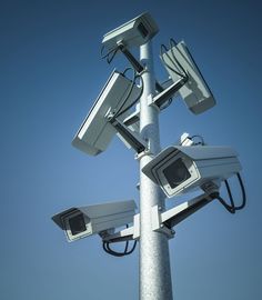 two cameras on top of a pole with blue sky in the background