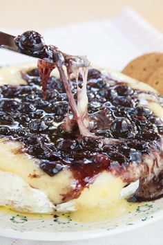 a plate topped with blueberry cheesecake covered in syrup next to a cracker