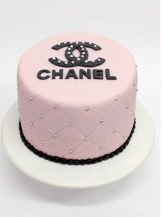 a pink chanel cake on a white plate with black lettering and pearls around the edges