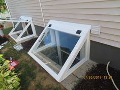 two white windows sitting on the side of a house