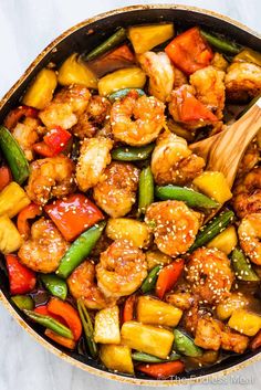 a skillet filled with shrimp, pineapples and peppers