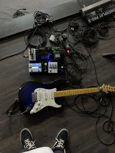 an electric guitar and other electronic equipment on the floor next to a person's feet