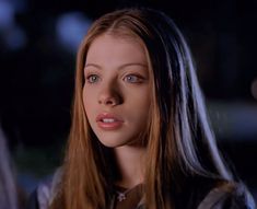 a close up of a woman with long hair and blue eyes looking at the camera