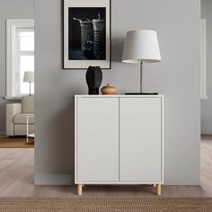 a white cabinet sitting next to a lamp on top of a hard wood floored floor