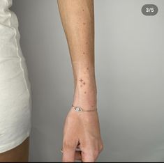 a woman's arm with a tiny star tattoo on it