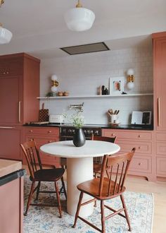 a white table and chairs in a room with pink cabinets on either side of it