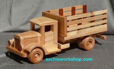 a wooden toy truck sitting on top of a gray cloth covered surface with the words ashwood shop written below it