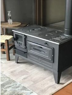 a black stove top oven sitting on top of a wooden floor next to a table