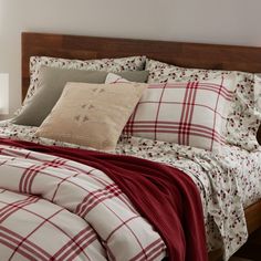 a bed with red and white plaid comforter on it's headboard next to a night stand