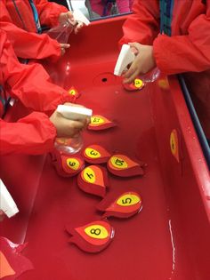 two children are playing with numbers on a red tray