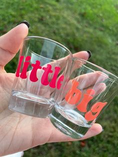 two glasses with the words little big and little written on them are held in someone's hand