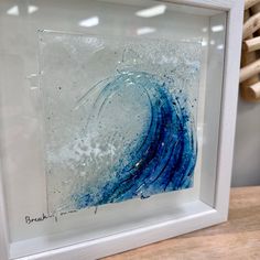 a painting in a white frame sitting on top of a table