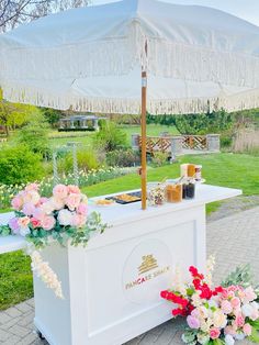 an outdoor bar with flowers and candles on the table next to it is covered by an umbrella