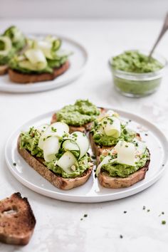 two white plates topped with sandwiches covered in guacamole