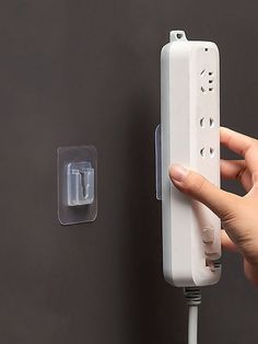 a person holding a wii remote in their left hand and plugged into the wall