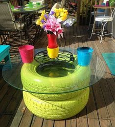 a table made out of an old tire with flowers in the center and cups on top