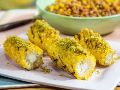 corn on the cob with mustard and seasoning next to a bowl of beans