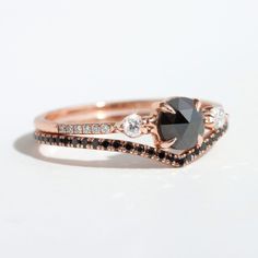 a close up of a black diamond ring on a white surface with diamonds around it