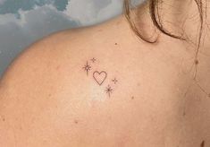 the back of a woman's shoulder with a small heart and stars tattoo on it