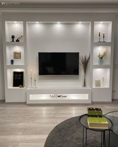 a modern living room with built in shelves and a flat screen tv on the wall