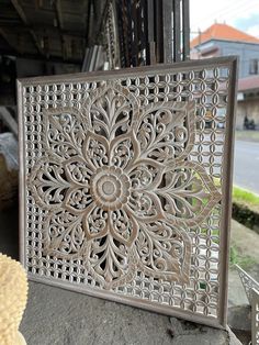 an intricately carved metal panel on the side of a building with a street in the background