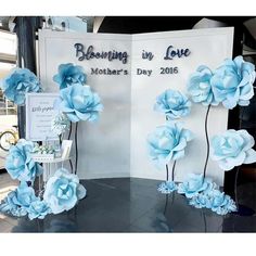 blue flowers are on display in front of a sign that says blessing in love mother's day