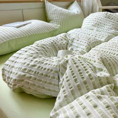 an unmade bed with green and white sheets