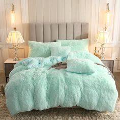 a bed covered in blue fluffy blankets and pillows