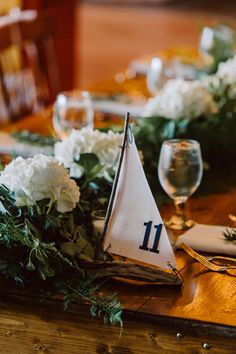 a sailboat is on the table with flowers and greenery in front of it