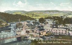 an old photo of a town with mountains in the back ground and water running through it