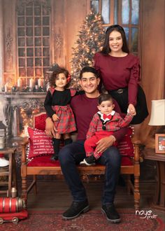 a family poses for a photo in front of a christmas tree