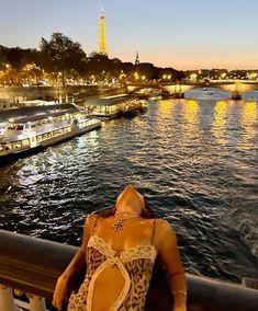 a woman in a leopard print bathing suit looking out over the water at boats and lights