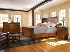 a bed room with a neatly made bed and wooden furniture on the hardwood flooring