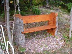 a wooden bench sitting in the middle of a forest next to a small tree stump