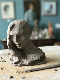 a clay head sitting on top of a table next to a piece of art work