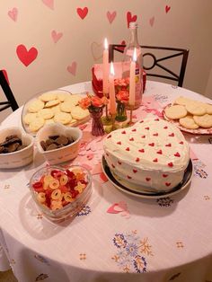 a table topped with cake and cookies next to bowls of desserts on top of a table