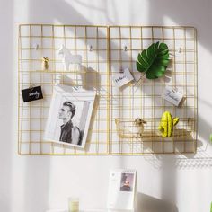 a white table topped with a metal shelf filled with pictures and other items next to a window