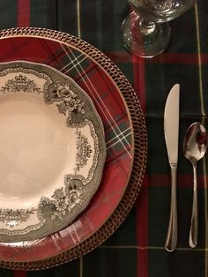 an empty plate and silverware on a plaid table cloth