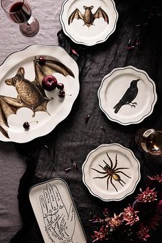 the table is set with plates, napkins and candlesticks for halloween decorations