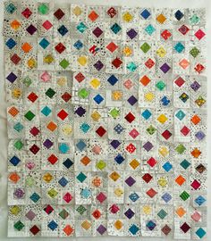 a quilt made with squares and dots on the side, all in different colors as well as white