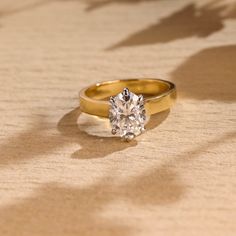 a diamond ring sitting on top of a wooden table next to shadow from the sun