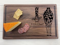 a wooden cutting board with cheese, crackers and giraffes on it