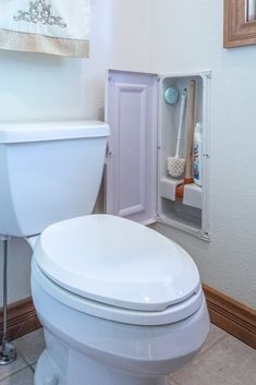 a white toilet sitting in a bathroom next to a wall mounted toothbrush dispenser