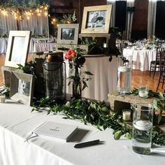 the table is set up for an event with flowers, candles and pictures on it