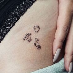 a woman's stomach with two sea animals and a shell tattoo on her belly