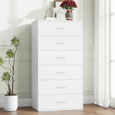 a white chest of drawers sitting next to a potted plant