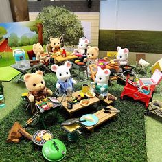 there are many stuffed animals sitting at the picnic table together on the grass in front of pictures