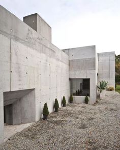 there are many trees in front of the concrete building that looks like it is made out of cement