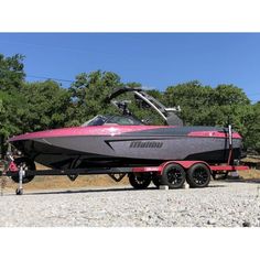 a black and pink boat is parked on the gravel